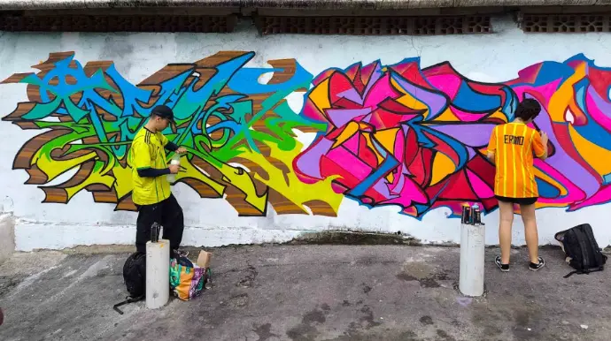 Artistas finalizam mural com traços vibrantes e cores intensas no projeto Graffiti Esperança.